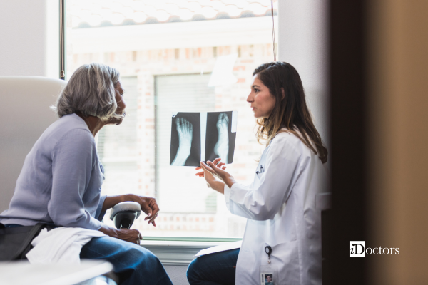 Medico mostra a una paziente le immagini radiografiche del piede durante la valutazione dell’esame.