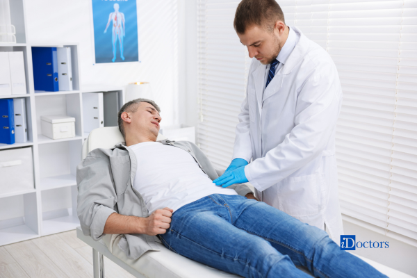 Medico che valuta l'addome di un paziente steso su un lettino durante una visita specialistica.