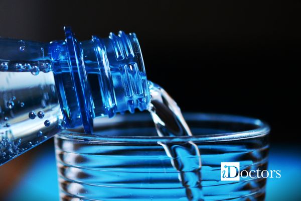 Acqua minerale versata da una bottiglia in un bicchiere