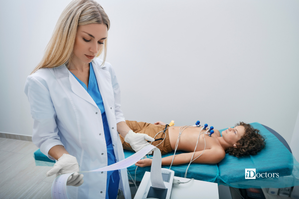 Dottoressa mentre sta leggendo il tracciato di un ecg di un piccolo paziente steso sul lettino durante una visita specialistica.