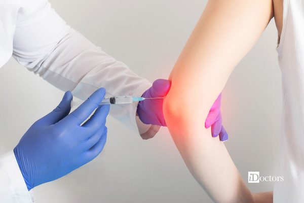 Mano di un medico che tiene una siringa che inserisce nel gomito di un paziente.