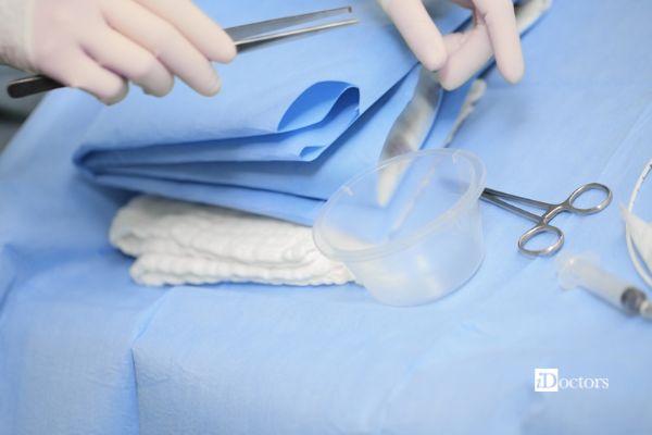 Operatore sanitario con guanti prepara garze e strumenti per una medicazione chirurgica
