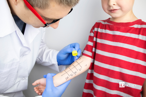 Medico con occhiali che ha in mano un contagocce che sta per poggiare sul braccio di un bambino.