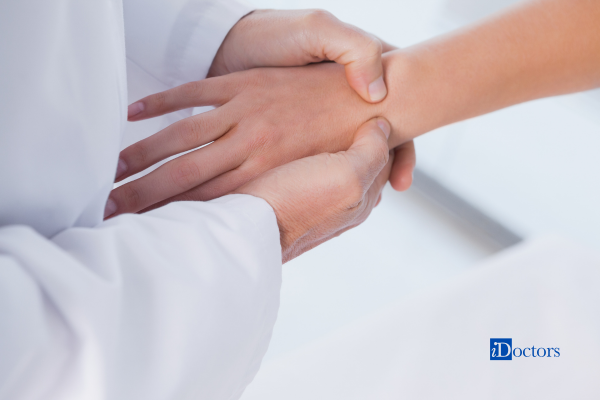 Mano del medico che sta palpando la mano di un paziente durante una visita.
