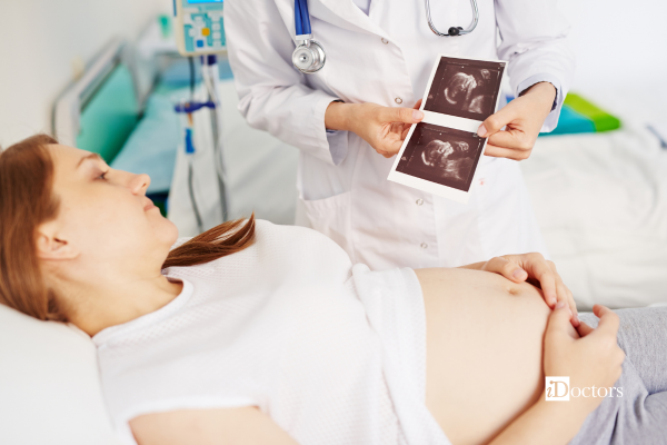 Paziente incinta sdraiata che guarda l'ecografia del suo bambino dalle mani della dottoressa.