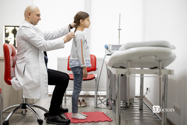 Dottore che sta verificando la postura di una bambina durante una visita specialistica.