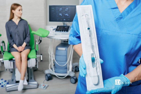 Professionista sanitario mostra una spirale intrauterina (IUD) prima dell’inserimento, con la paziente sullo sfondo.