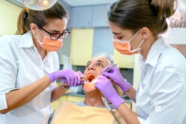 Odontoiatra esegue un’estrazione dentale con una pinza, assistita da un’operatrice.